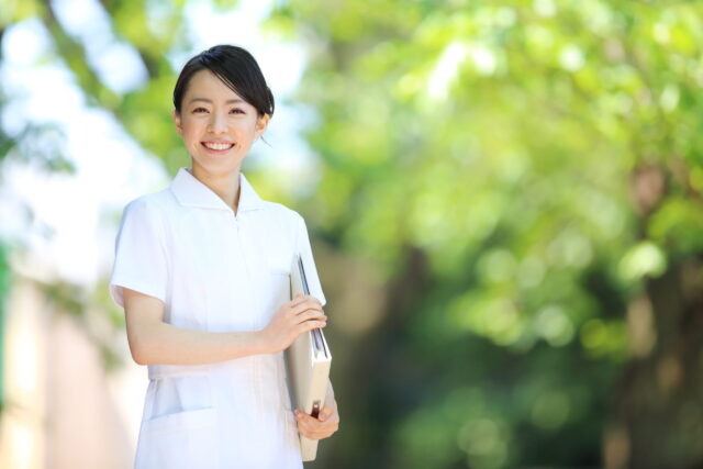 緑の木の前に立つ看護師