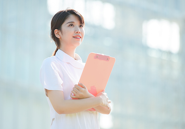 バインダーを抱えてほほ笑む看護師