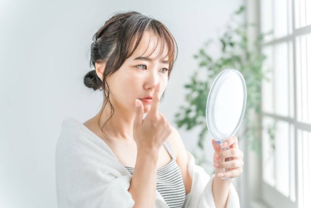 鏡で肌を確認する女性